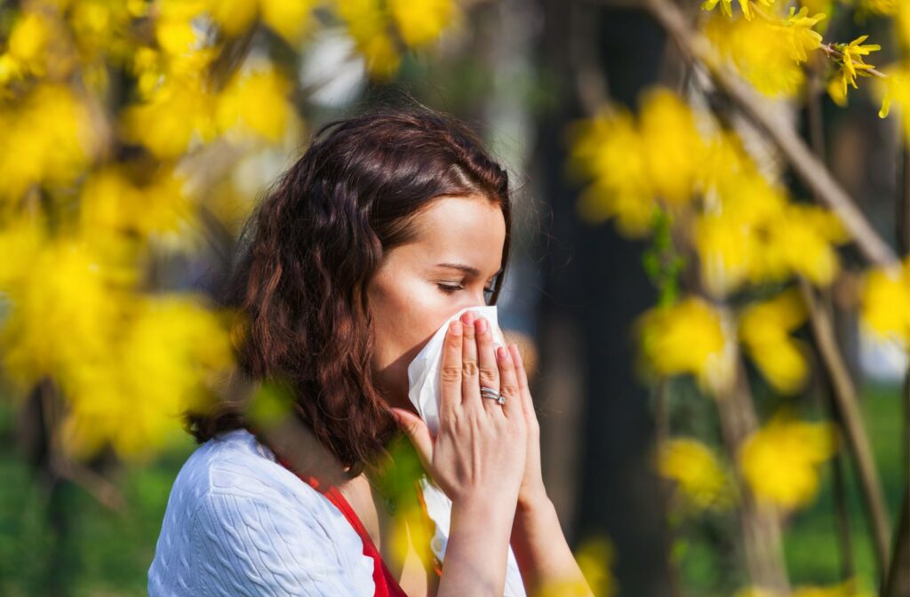 A woman using a tissue to blow her nose due to seasonal allergies