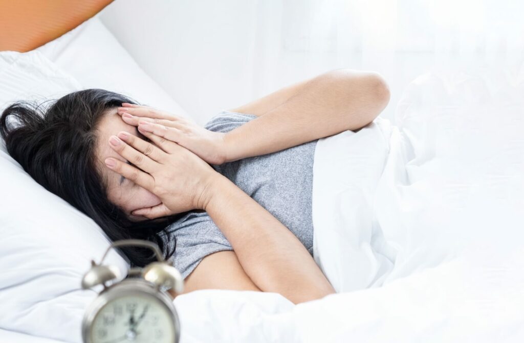 A woman is rubbing her eyes after waking up due to dry eye symptoms in the morning.