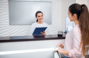 A friendly eye clinic receptionist gathers a patient's insurance details.