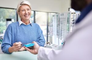 A smiling older adult pays for the portion of their eye appointment that wasn't covered by VSP insurance.