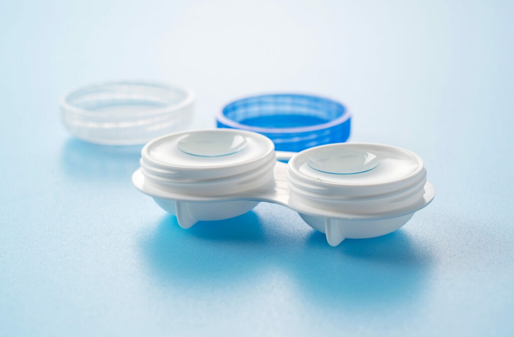 An open contact lens case sits on a plain background with lenses inside.