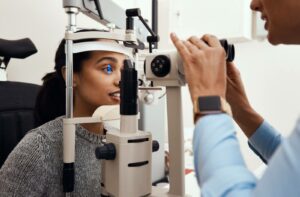An optometrist examines their patient's eyes during a contact lens fitting.