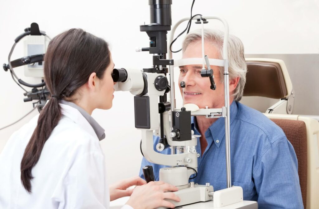 Optometrist performing an eye exam on an older male patient using a slit lamp.
