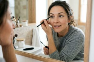 A mascara tube, applicator wand, and an eyeliner pencil are used for eye makeup.